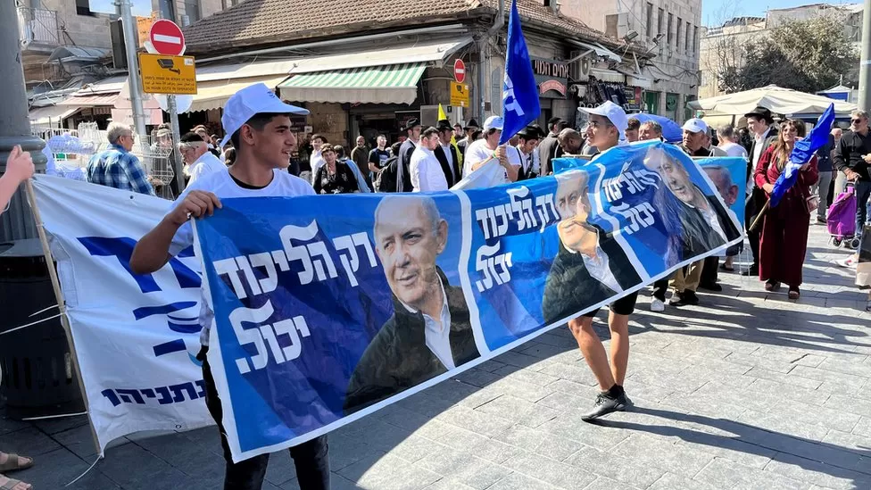 “Is Netanyahu coming back?” I ask an activist from his Likud party unfurling a large banner at the entrance to Jerusalem’s bustling Mahane Yehuda Market.